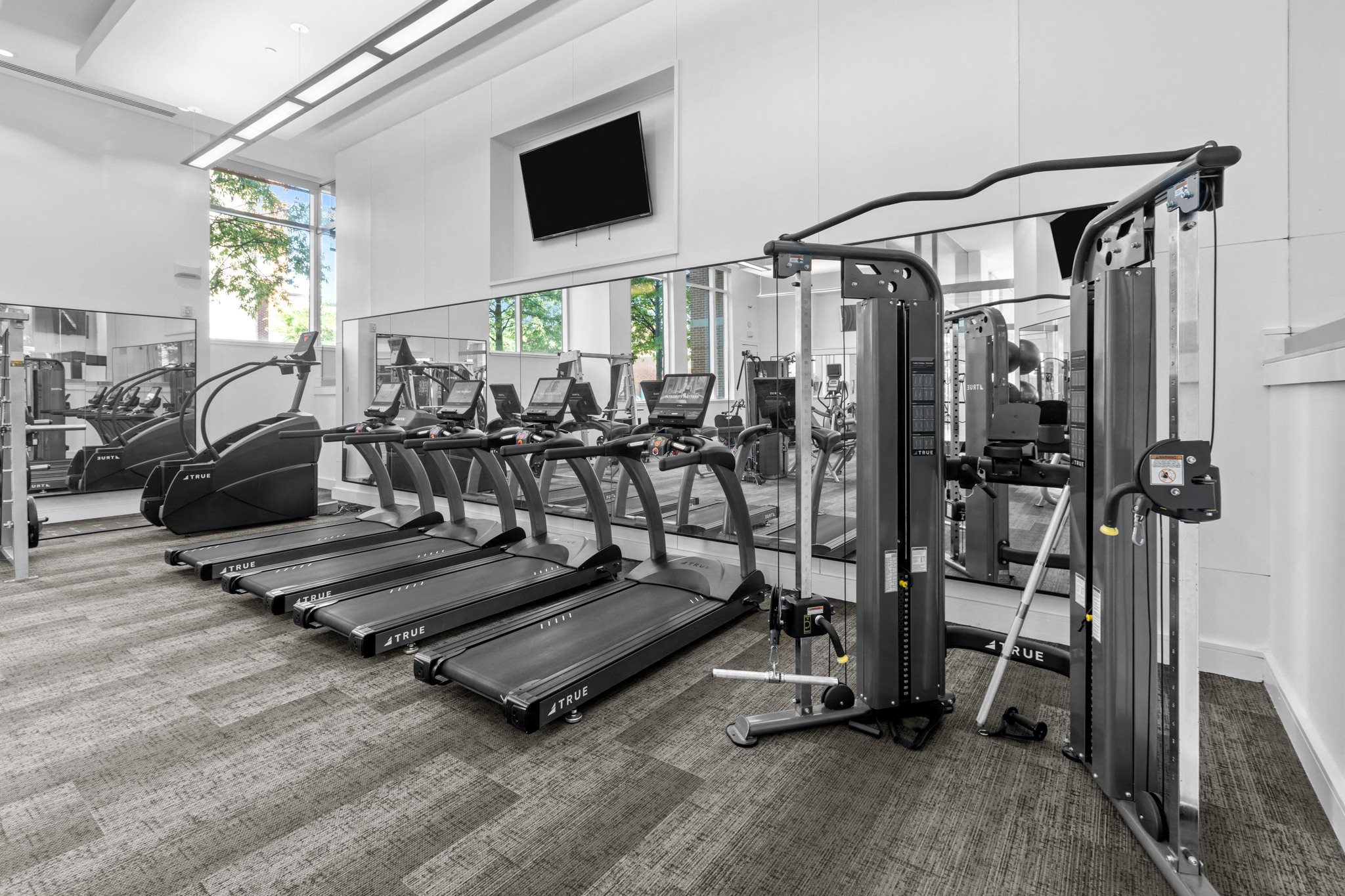 a gym with cardio equipment and a tv on the wall